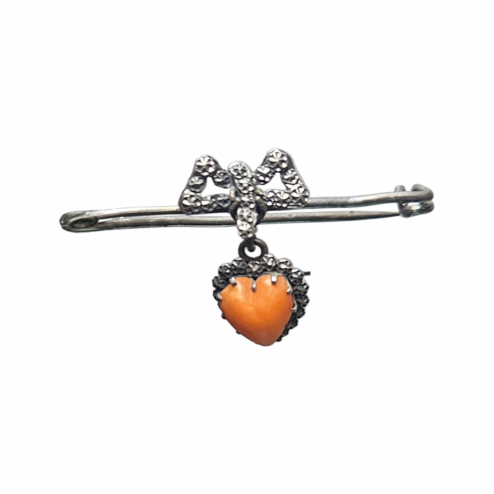 Vintage 1930s–40s sweetheart safety pin brooch with sculpted bow and dangling orange heart cabochon. Romantic vintage costume jewellery.