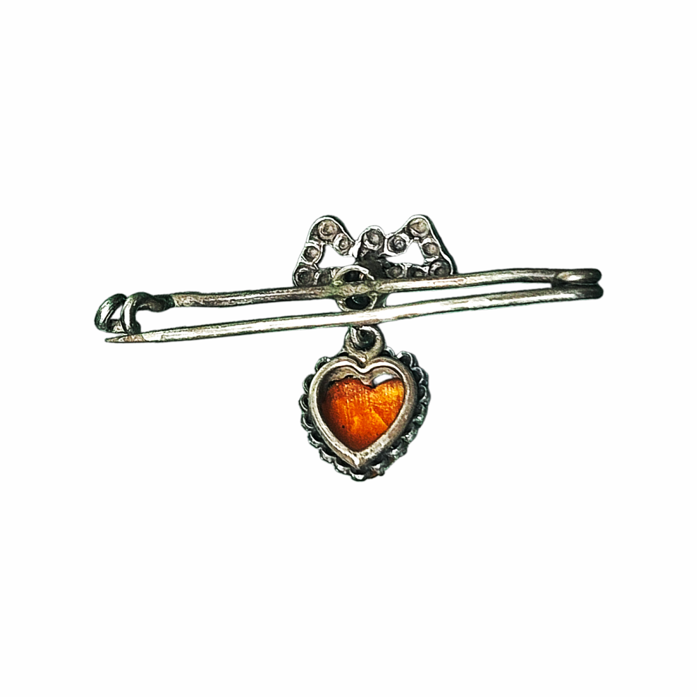 Vintage 1930s–40s sweetheart safety pin brooch with sculpted bow and dangling orange heart cabochon. Romantic vintage costume jewellery.