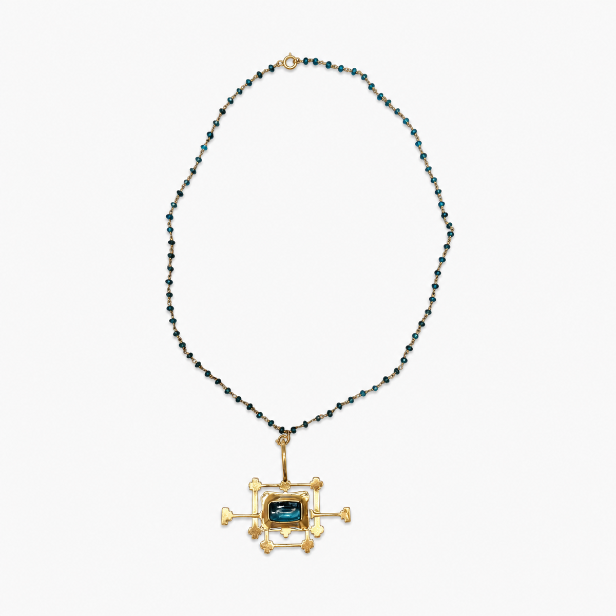 An unusual vintage artisan necklace combining a delicate strand of faceted petrol-blue beads with an oversized architectural pendant in warm gold-tone metal and petrol blue glass stone insert
