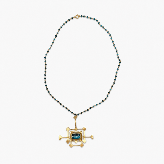 An unusual vintage artisan necklace combining a delicate strand of faceted petrol-blue beads with an oversized architectural pendant in warm gold-tone metal and petrol blue glass stone insert
