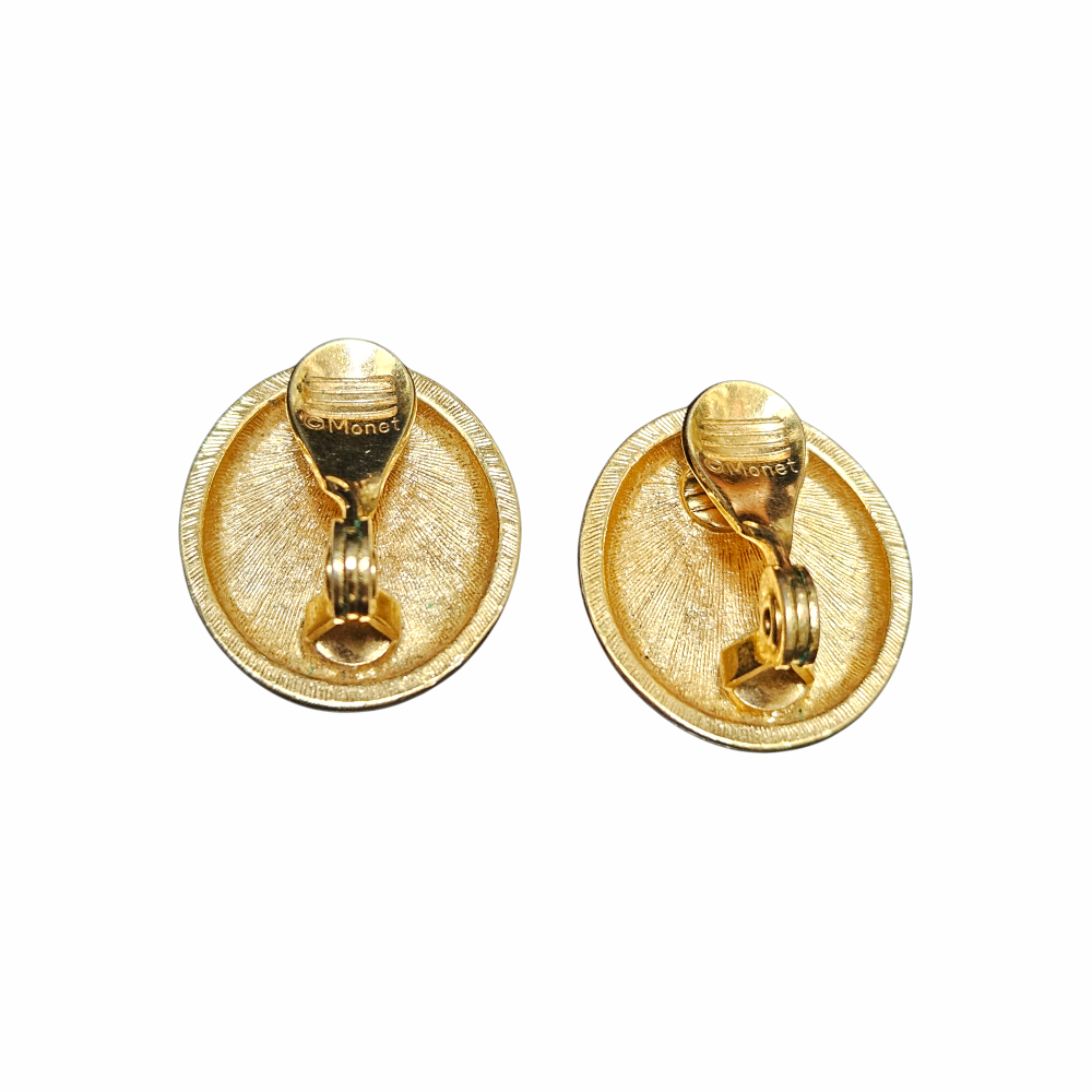 Vintage 1980s Monet red oval clip-on earrings with glossy cabochon-style centres, textured gold-tone frames and signed Monet backs.