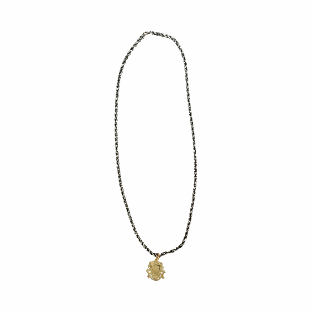 Vintage India silver heraldic shield pendant on twisted rope chain with pierced foliate detailing and aged mixed-metal finish.