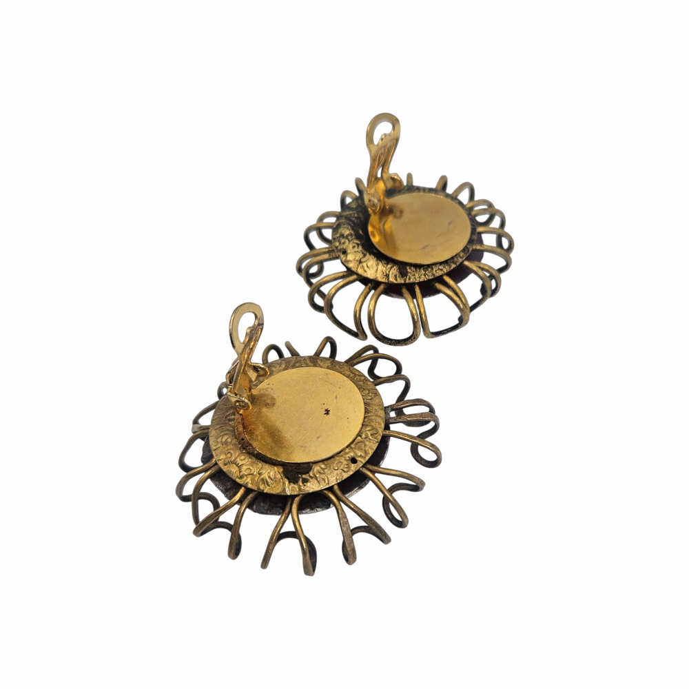 Oversized artisan brutalist vintage clip-on earrings with purple glass centres and sculptural brass-tone cage detailing, approx. 5 cm diameter.